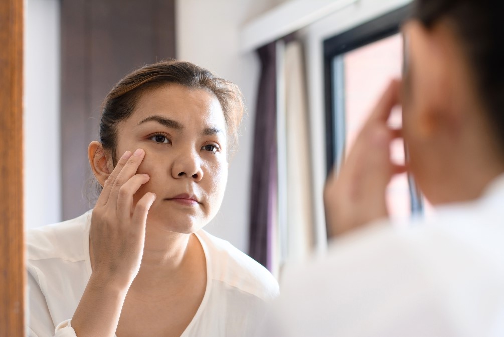 woman looking in mirror and concerned about her face