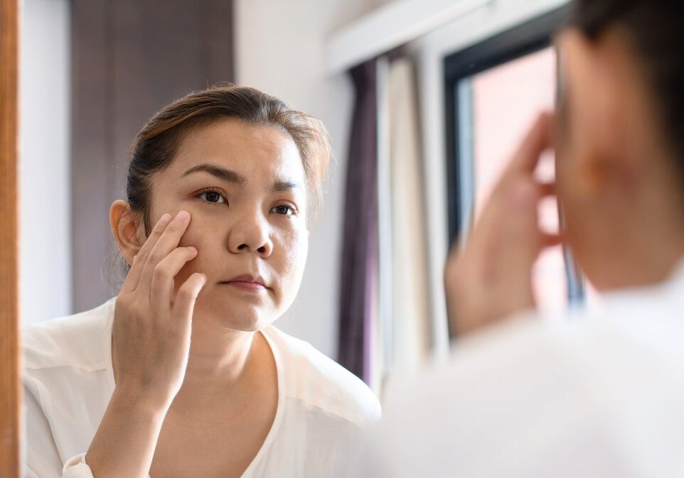 woman looking in mirror and concerned about her face