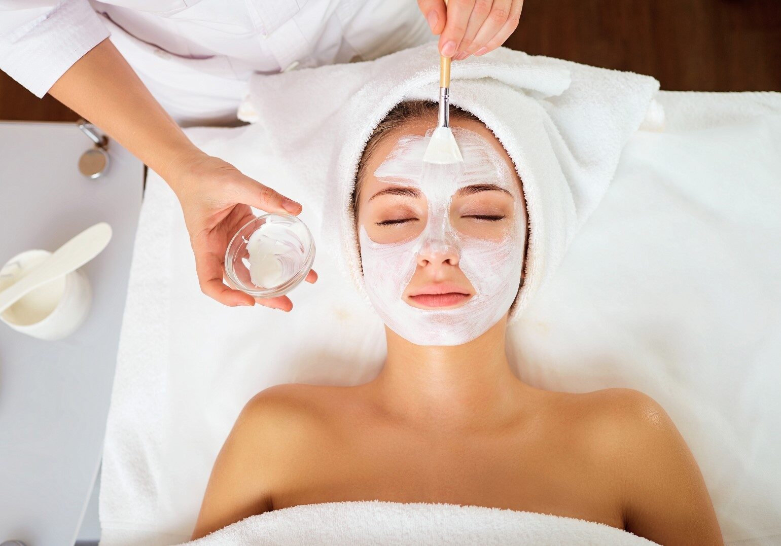 staff applying white mask on customer's face